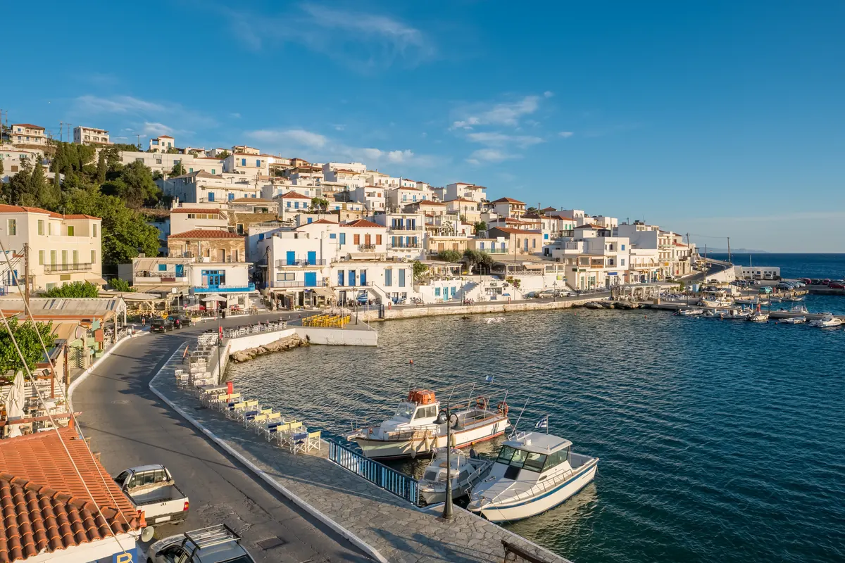 Το waterfront του Μπατσίου με τα τραπέζια των ταβερνών και τα καΐκια στο λιμανάκι, Άνδρος