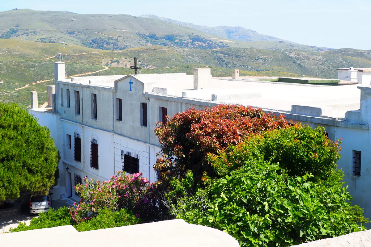 Λευκό μοναστήρι με ανθισμένο κήπο και βουνά στο βάθος, Άνδρος
