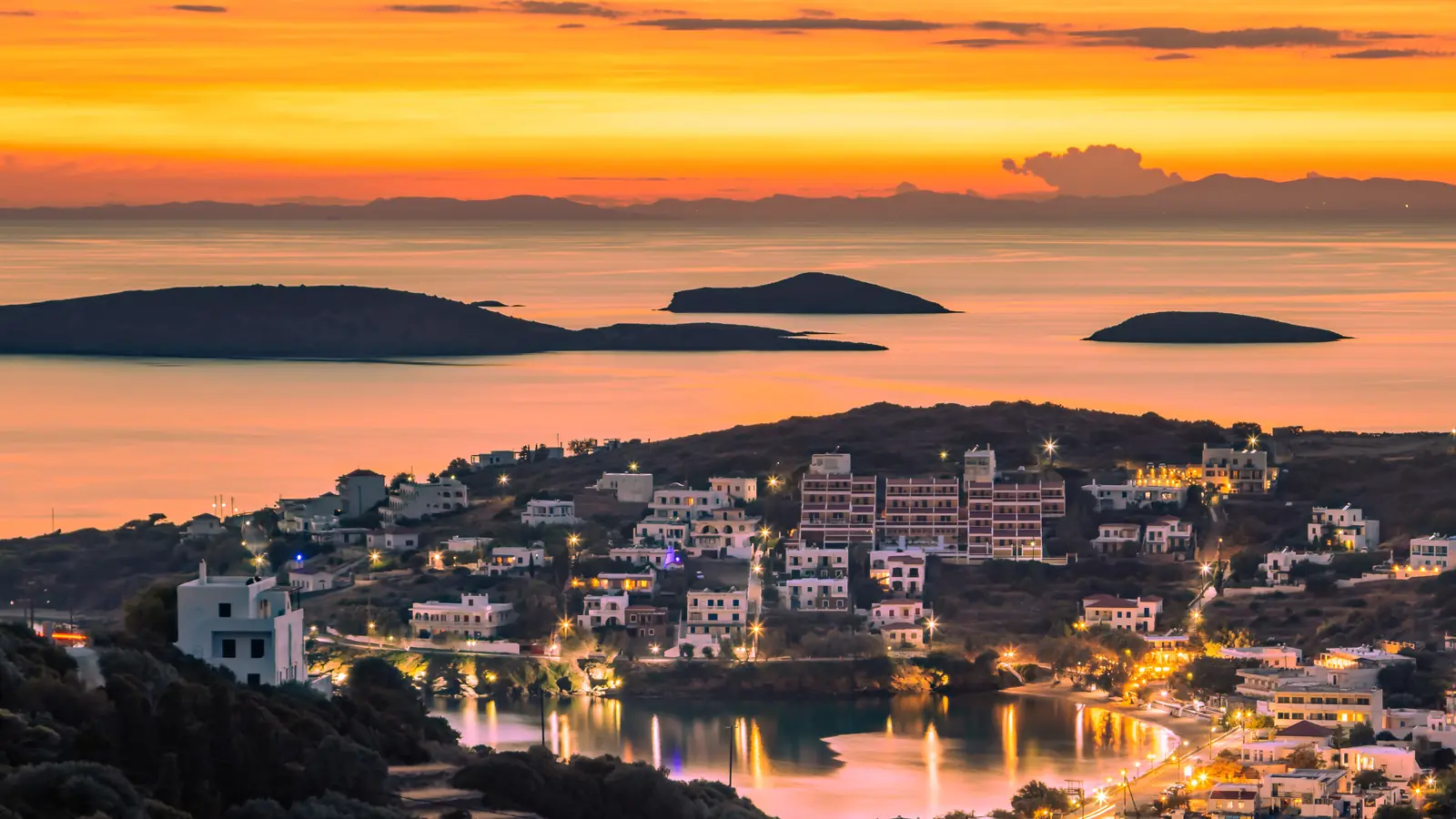 Ηλιοβασίλεμα πάνω από το Μπατσί, με τα φώτα του όρμου και νησίδες στο βάθος, Άνδρος