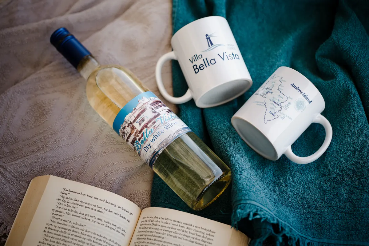 Tassen und ein Handtuch mit dem Logo von Bella Vista Design Studios, neben einer Flasche Wein